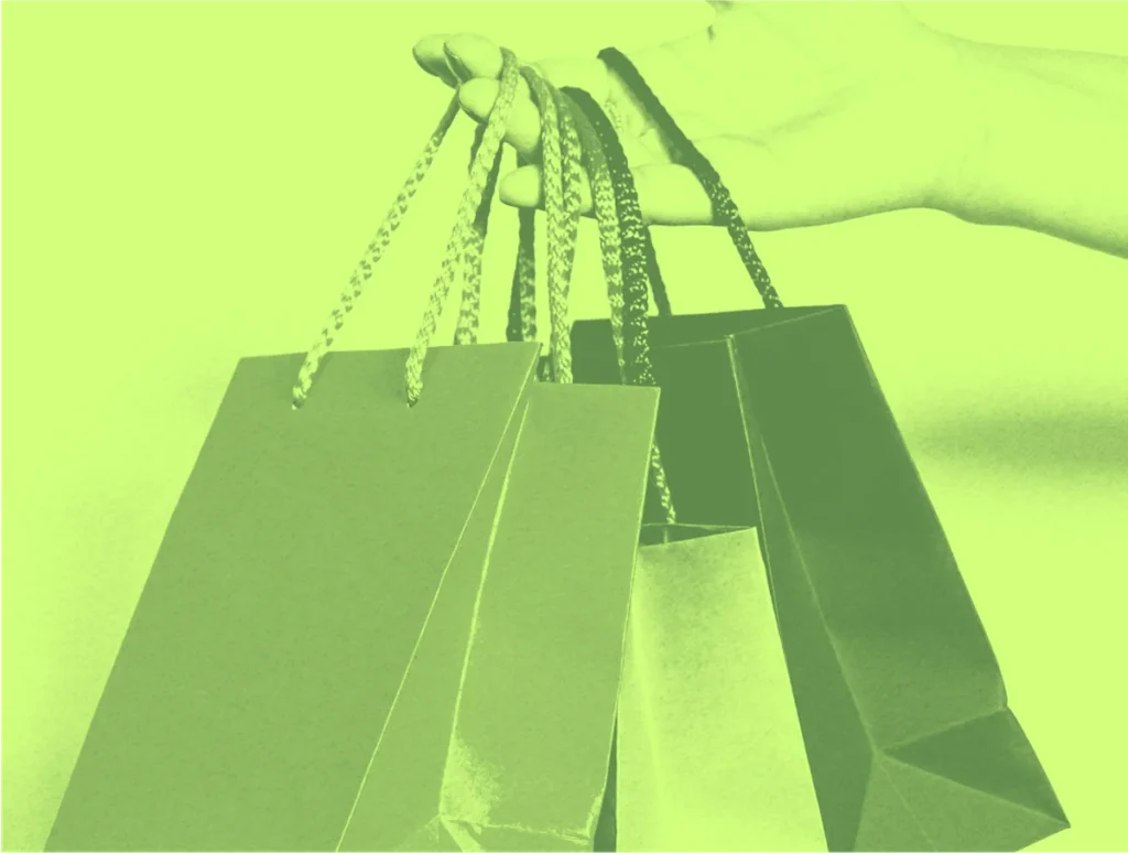 Hand holding paper shopping bags with green filter
