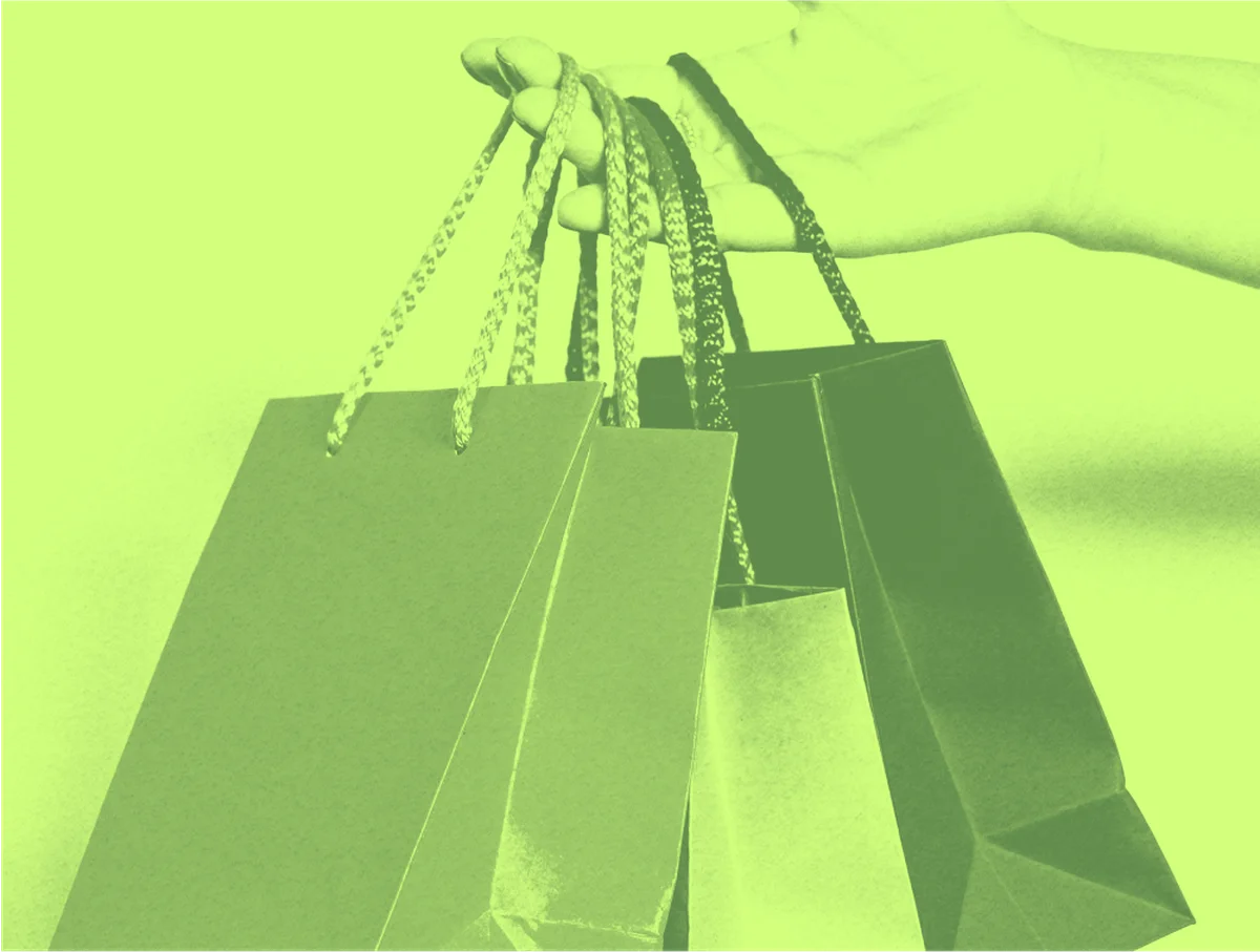 Hand holding paper shopping bags with green filter