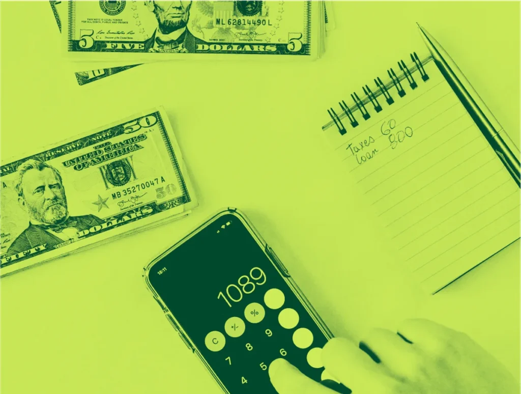 Hand using calculator app with US currency and tax notebook