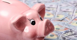Yellow piggy bank on a stack of US dollar bills