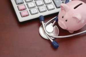 Piggy bank, calculator and stethoscope on a kitchen table