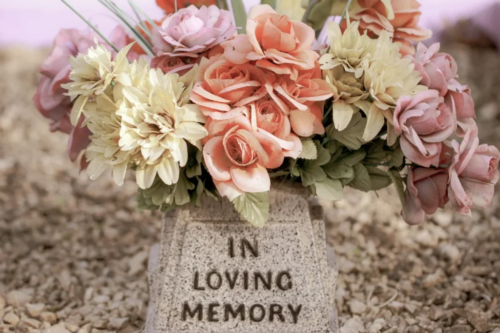 Pastel artificial flowers in a stone urn-inscribed vase on a cemetery