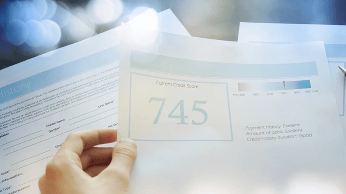 Hand holding a credit report showing a 745 score on a 300 to 850 scale