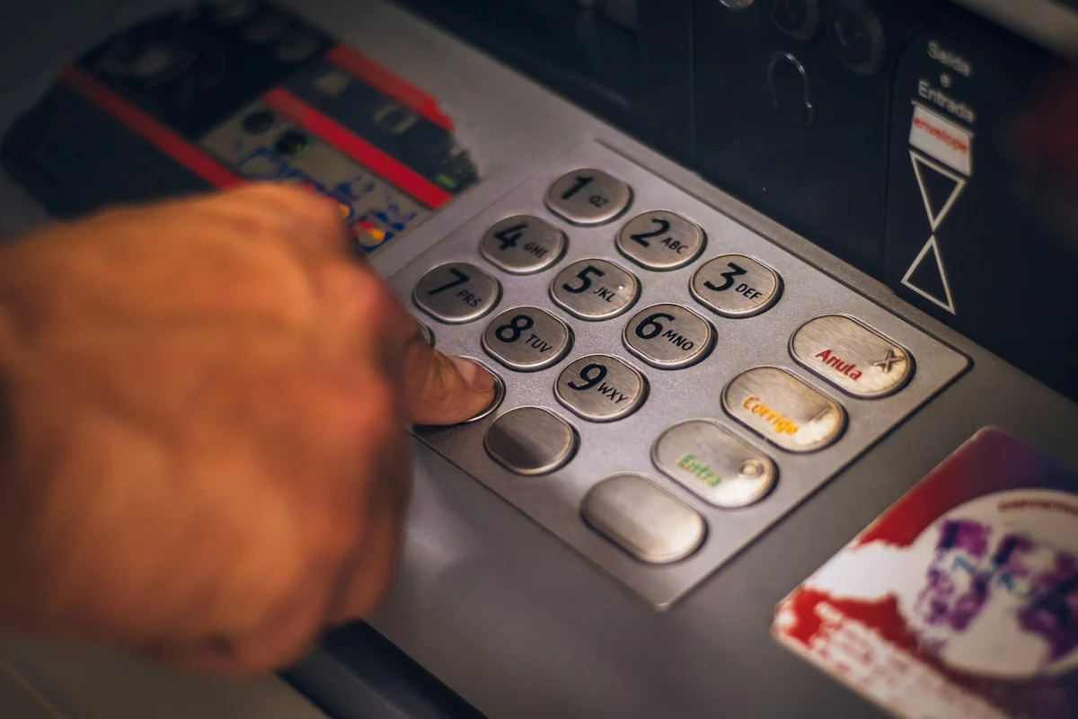 Hand pressing a button on an ATM keypad