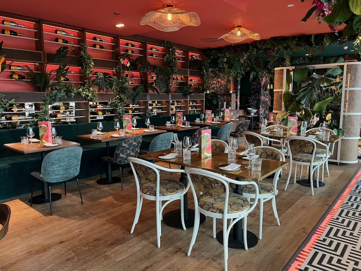 Stylish plant-filled restaurant interior with wine shelves