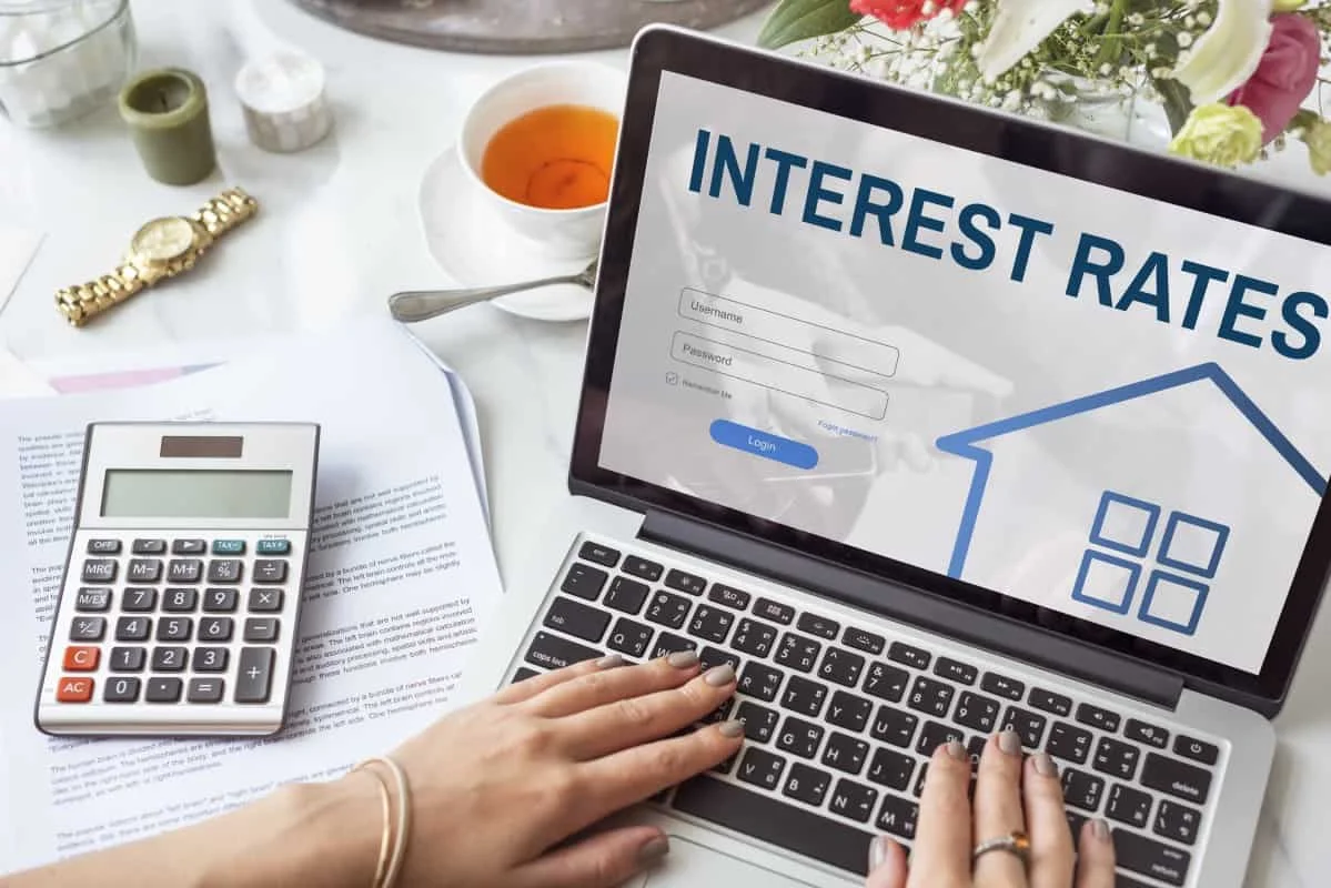 Hands typing on laptop showing interest rate figures