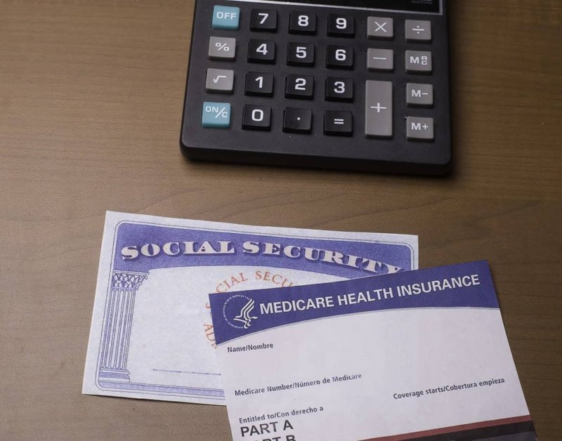 Calculator beside Medicare and Social Security cards on desk