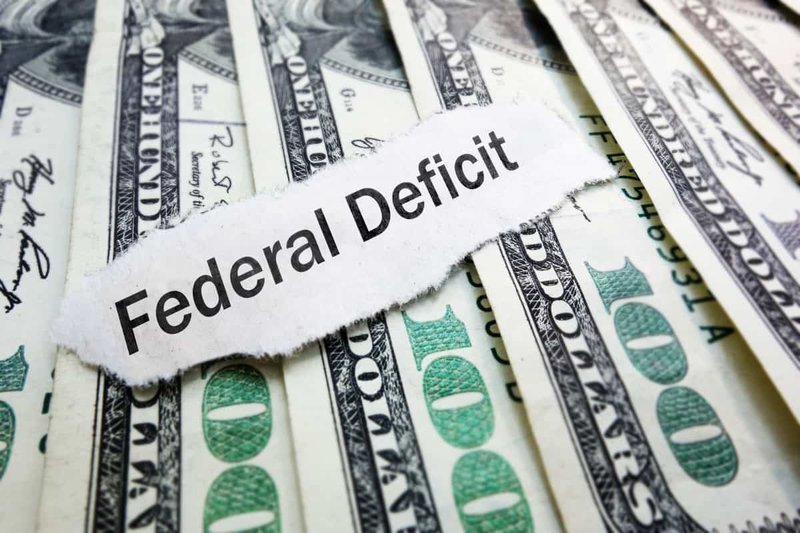 Torn federal deficit strip over U.S. dollar bills